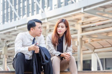 İş adamı ve kadın birlikte merdivenlerde oturuyor, Asyalı genç iş adamları sabah tartışıyor.