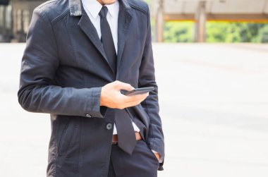 Cep telefonlu bulanık şehir arkaplanı kullanan genç adamın yakın çekimi