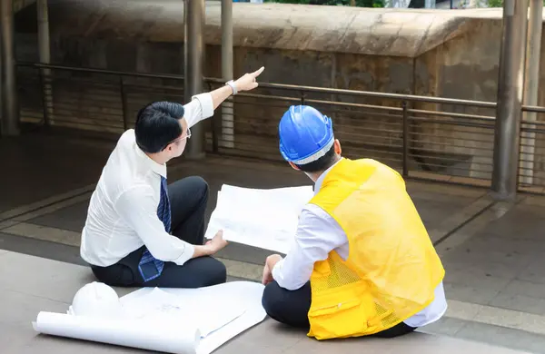 Engineer and fourman worker team with drawing paper planning projects in construction sit