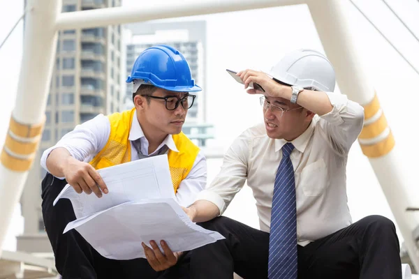 Serious engineer man team with drawing paper planning projects in construction site