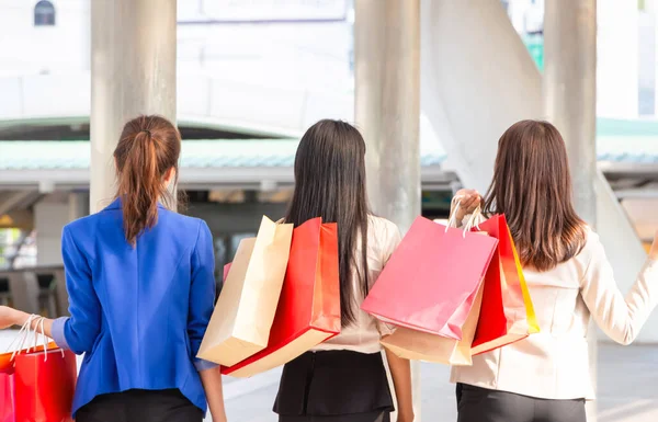 Back view of a Group of young women carrying shopping bags while walking along the street. Happy Life and Shopping Concepts