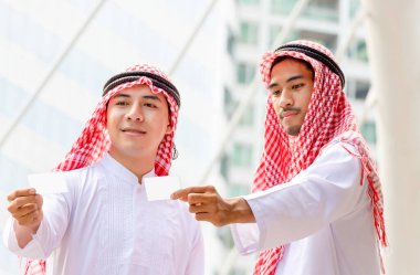 İş adamları, elinde kredi kartı tutan Arap Ortadoğu İşadamı için boş kartvizit tutuyor.