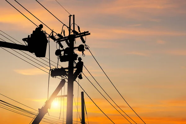 Silhouette of Electrician officer team climbs a pole and using a cable car to maintain a high voltage line system, Shadow of Electrician lineman repairman worker team at climbing work on the electric post power pole