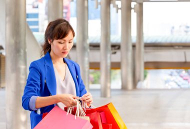 Sokakta yürürken alışveriş torbaları taşıyan meşgul genç bir Asyalı kadın. Alışveriş kavramları