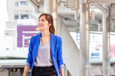 Gülümseyen Asyalı iş kadını dışarıda yürüyor