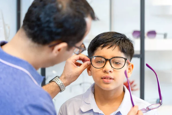 光学店で眼鏡を選ぶインド人の父と息子 — ストック写真