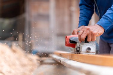 Marangoz ahşap, ahşap işçiliği ve elektrikli aletle planlama tahtalarını düzeltmek için elektrikli planör kullanıyor.