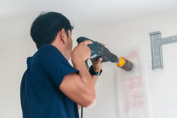 Technician man drilling to concrete wall with core drill machine to install modern air conditioner, Maintenance and servicing concepts
