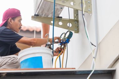 Klima tamircisi modern klima sistemini kontrol ediyor ve tamir ediyor, teknisyen ekibi havalandırma sistemini kontrol ediyor.