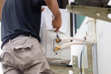 İngiliz anahtarı kullanan teknisyen, modern havalandırma sistemini tamir ediyor.