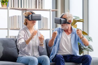 Üst düzey yetişkin çift koltukta oturup sanal gerçeklik gözlükleriyle eğleniyor, mutlu yaşlı teknoloji konsepti