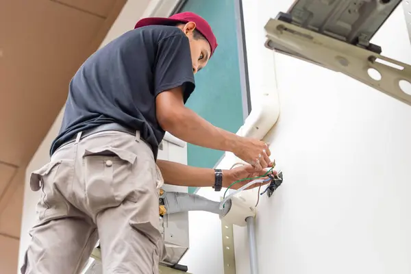 Technician connecting electric wires to install new air conditioning, repair service, and install new air conditioner concept