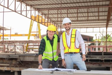 Mühendis ve ustabaşı işçi ekibi inşaat alanındaki inşaat alanındaki mühendis ve inşaatçıları kontrol ediyor.