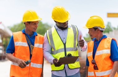 Mühendis ve inşaat ekibi inşaat sahasında, ustabaşı ve işçi kontrol projesini ön döküm fabrikasında tartışıyorlar.