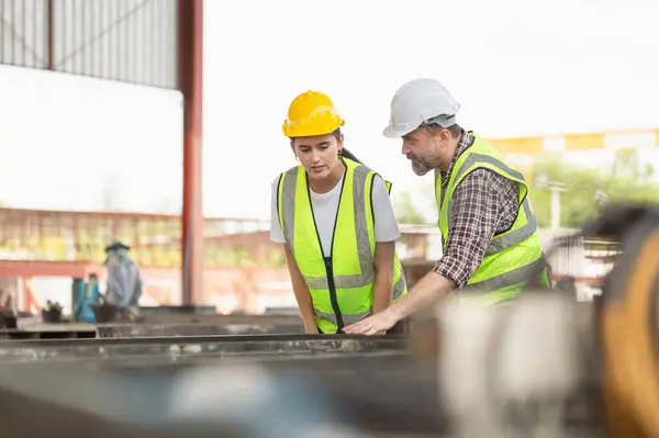 Mühendis ve kadın ustabaşı inşaat öncesi beton fabrikası projesini kontrol ediyor. Kafkasyalı mühendis ve işçi inşaat üzerinde tartışıyor.