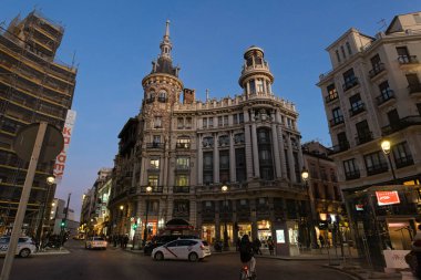 MADRID, SPAIN - 19 Şubat 2020 Meneses Binası 'nın muhteşem mimarisinin olduğu akşam sahnesi ve yanından geçen insanlar