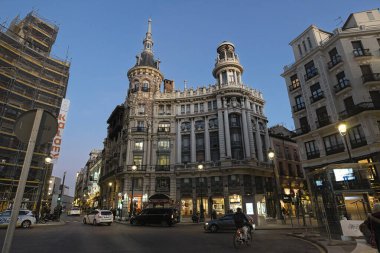 MADRID, SPAIN - 19 Şubat 2020 Meneses Binası 'nın muhteşem mimarisinin olduğu akşam sahnesi ve yanından geçen insanlar
