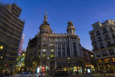 MADRID, SPAIN - 19 Şubat 2020 Meneses Binası 'nın muhteşem mimarisinin olduğu akşam sahnesi ve yanından geçen insanlar