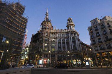 MADRID, SPAIN - 19 Şubat 2020 Meneses Binası 'nın muhteşem mimarisinin olduğu akşam sahnesi ve yanından geçen insanlar