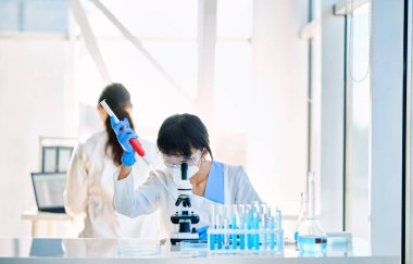 Modern bilim laboratuarında çalışan güzel kadın bilim adamı mikroskop slaytlarını hazırlıyor ve analiz ediyor. Kimya, Tıp, Biyoteknoloji konsepti