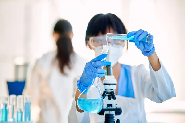 現代医学研究室で働く試験管に試薬を注ぐ研究を行う女性科学者 バイオテクノロジー 微生物学の発展 — ストック写真