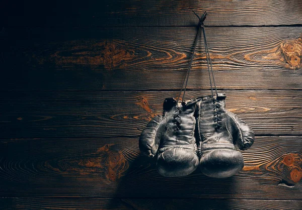 Old boxing gloves hang on nail on wooden wall with copy space for text. Retirement concept