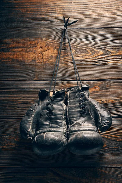 Old boxing gloves hanging on nail on wooden wall. Retirement concept. Sport