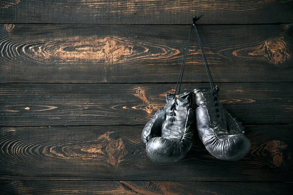 Old boxing gloves hanging on nail on wooden wall with copy space for your text. Retirement concept. Sport