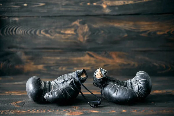 Old boxing gloves on wooden background. Sport. Retirement concept