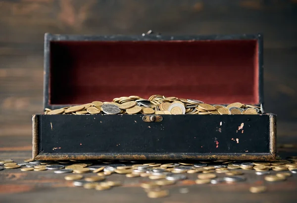 Open treasure chest filled with pile of coins. Finance, banking and investment concept.