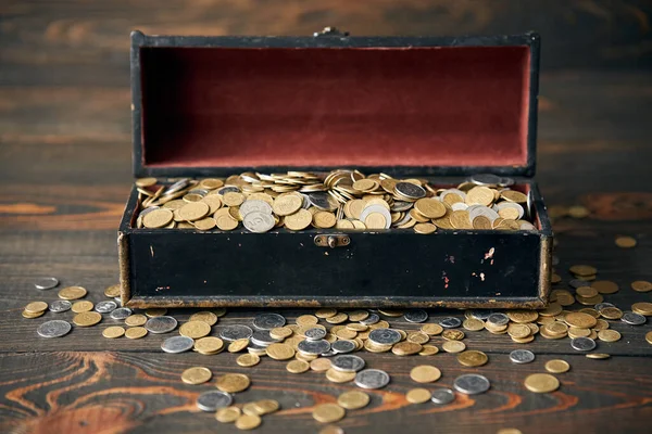 Open treasure chest filled with pile of coins. Finance, banking and investment concept.