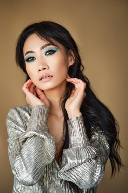 Saçlarına dokunan şehvetli güzel bir kadının yakın plan portresi kova arkaplanından kameraya bakıyor. Duygu, güzellik, makyaj, kozmetik konsepti