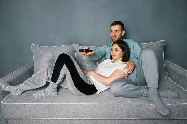 Young happy couple watching movie on TV while relaxing at home.