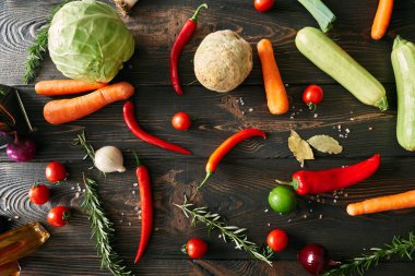 Top view of various fresh vegetables and herbs on dark wooden table. Food styling, culinary background, healthy eating concept