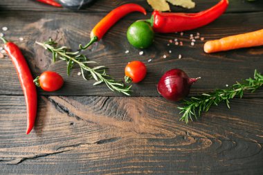 Top view of various fresh vegetables and herbs on dark wooden table with copy space. Food styling, culinary background, healthy eating concept