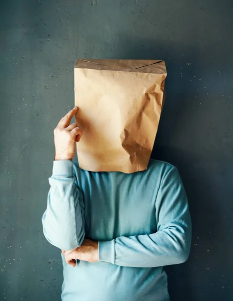 Man with a paper bag on head pointing to head with one finger. Great idea concept