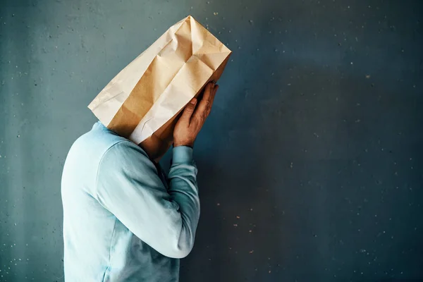 両手で目をカバーする頭の上に紙袋を持つ動揺した男 プロフィールビュー コピースペース 人々の感情の概念 — ストック写真