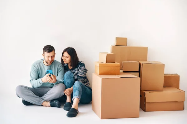 stock image Young married couple plans home improvement projects in their new apartment sitting on floor surrounded by cardboard boxes on moving day