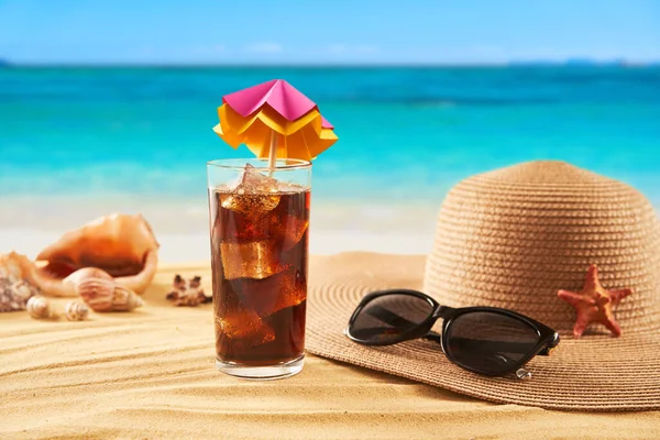 Relax on the beach. Summer time vacation concept. Straw hat, sunglasses and cocktail on the sand and sea background. Travel