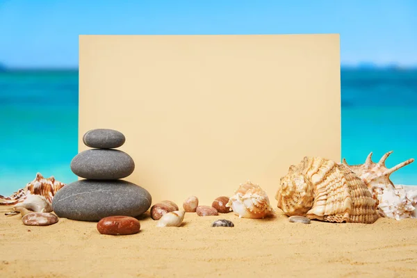 海を背景に夏の砂浜で貝殻や石のピラミッドとの招待状やグリーティングカードのモックアップ 休暇のコンセプト コピースペース — ストック写真