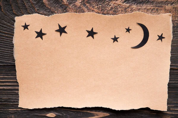 Postcard with moon and stars, paper art style. Greeting card, invitation mockup over dark wooden background. Flat lay, top view, copy space