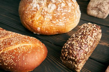 Ahşap zemin üzerinde çeşitli taze somunlar. Sağlıklı beslenme, yemek, fırın konsepti