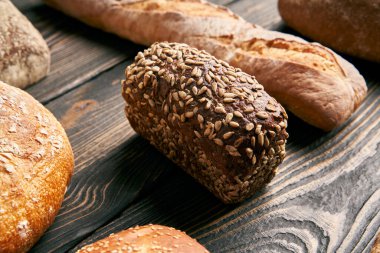 Koyu ahşap arka planda farklı ekmek türleri. Pastane, lezzetli yemek konsepti.