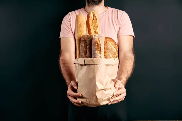 男は軽い背景の上に紙袋にパンのバゲットの新鮮な愛を保持しています パン屋 食のコンセプト — ストック写真