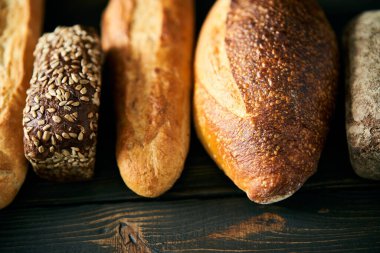 Ahşap zemin üzerinde çeşitli taze somunlar. Sağlıklı beslenme, yemek, fırın konsepti