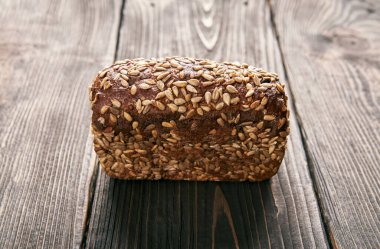 Ahşap masa arkasında bir somun taze çavdar ekmeği. Fırın, yemek konsepti.