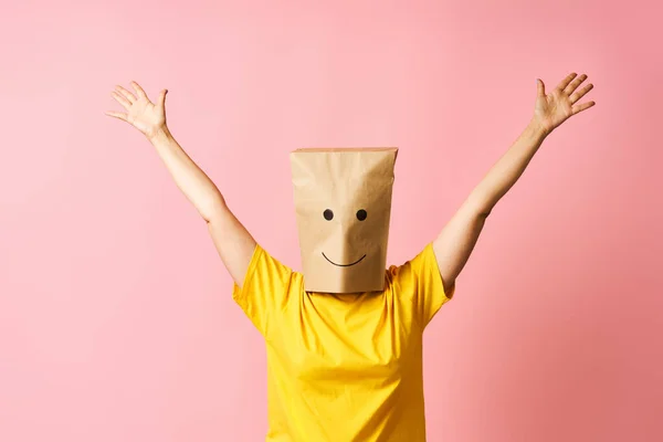 Woman with happy smile on the paper bag on head celebrating success with winner gesture. victory, triumph and emotions concept