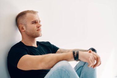 Yorgun bir adam yerde oturuyor yumuşak beyaz arka planda