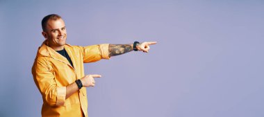 Mutlu gülümseyen adam mavi arkaplanda fotokopi alanını işaret ediyor.