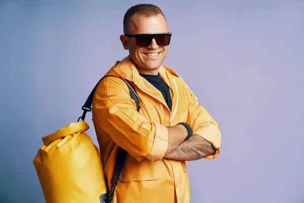 Trendy Lächelnder Mann Gelbem Regenmantel Und Sonnenbrille Über Blauem Studiohintergrund Stockfoto
